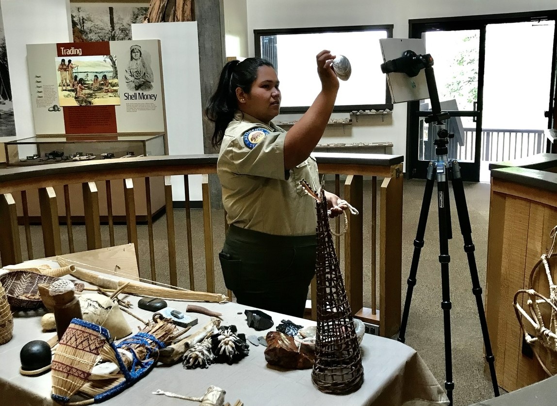 Image of Interpreter showing artifact to audience through a virtual presentation.
